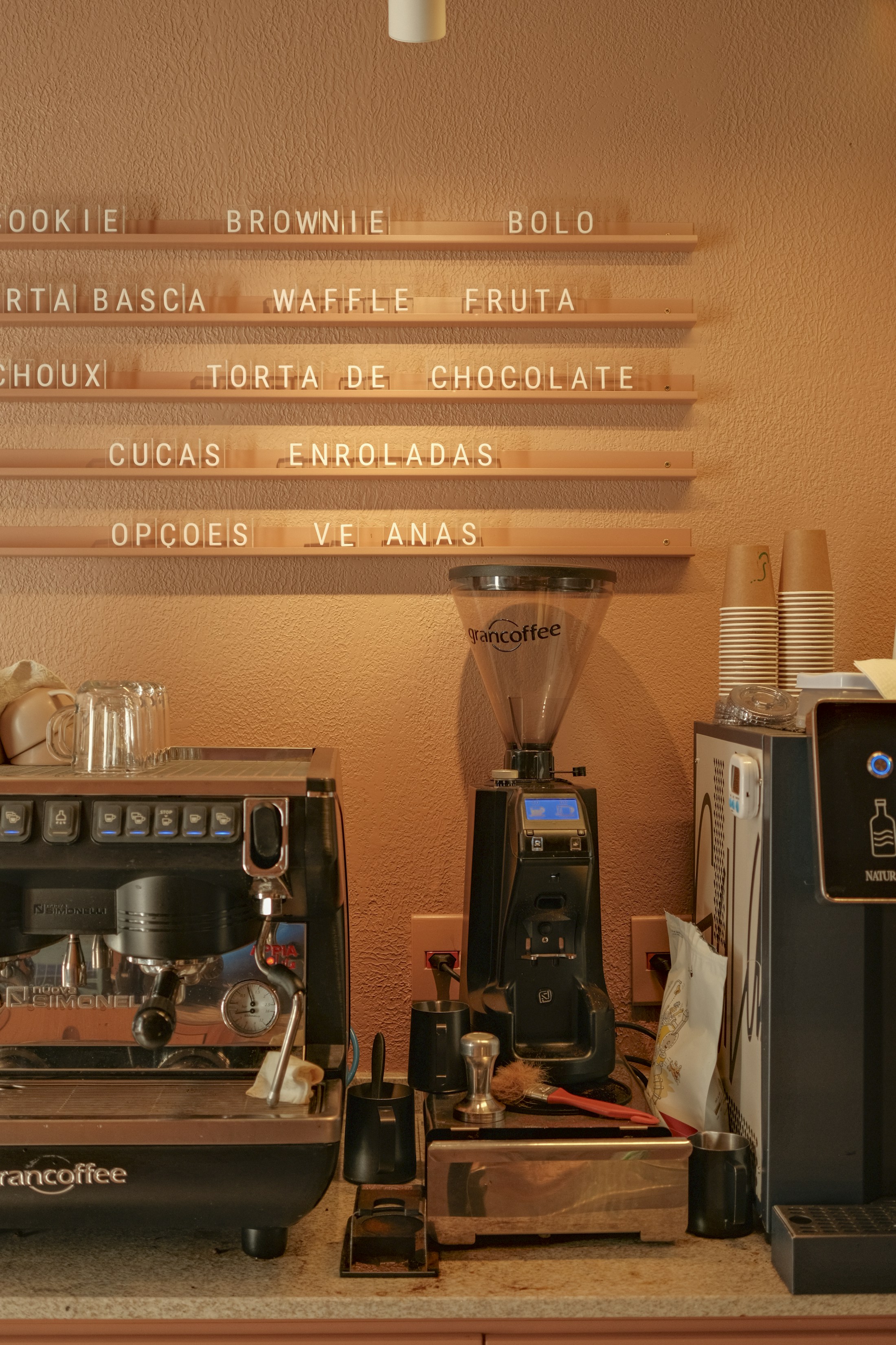 Kaffebarens disk med espressomaskine, kopper og menutavle